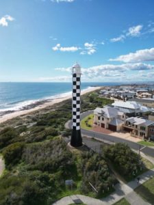 Aerial drone photo of a black and white checkered lighthouse in the city of Bunbury, Western Australia.